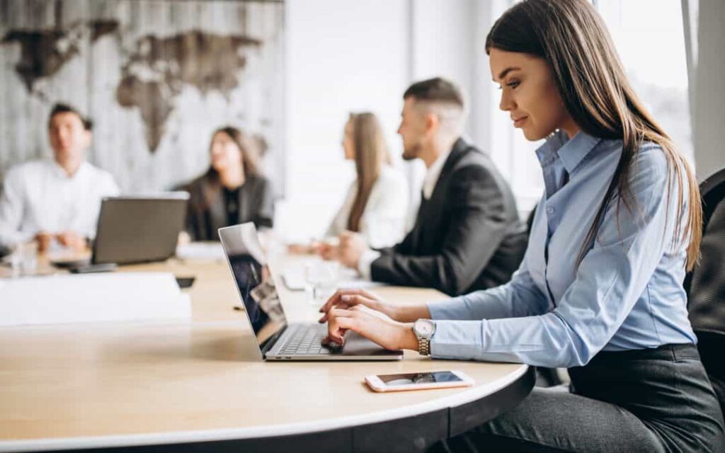 Mulher em destaque na imagem mexendo em um notebook