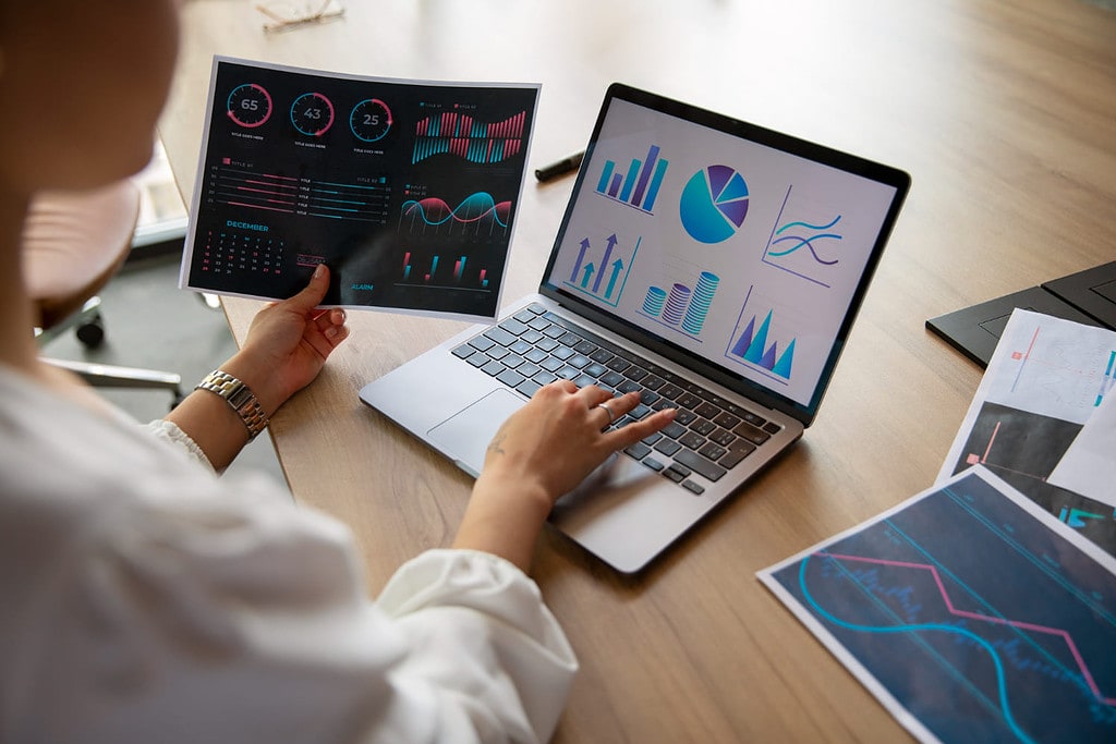 Mulher analisando gráficos no notebook e em uma impressão